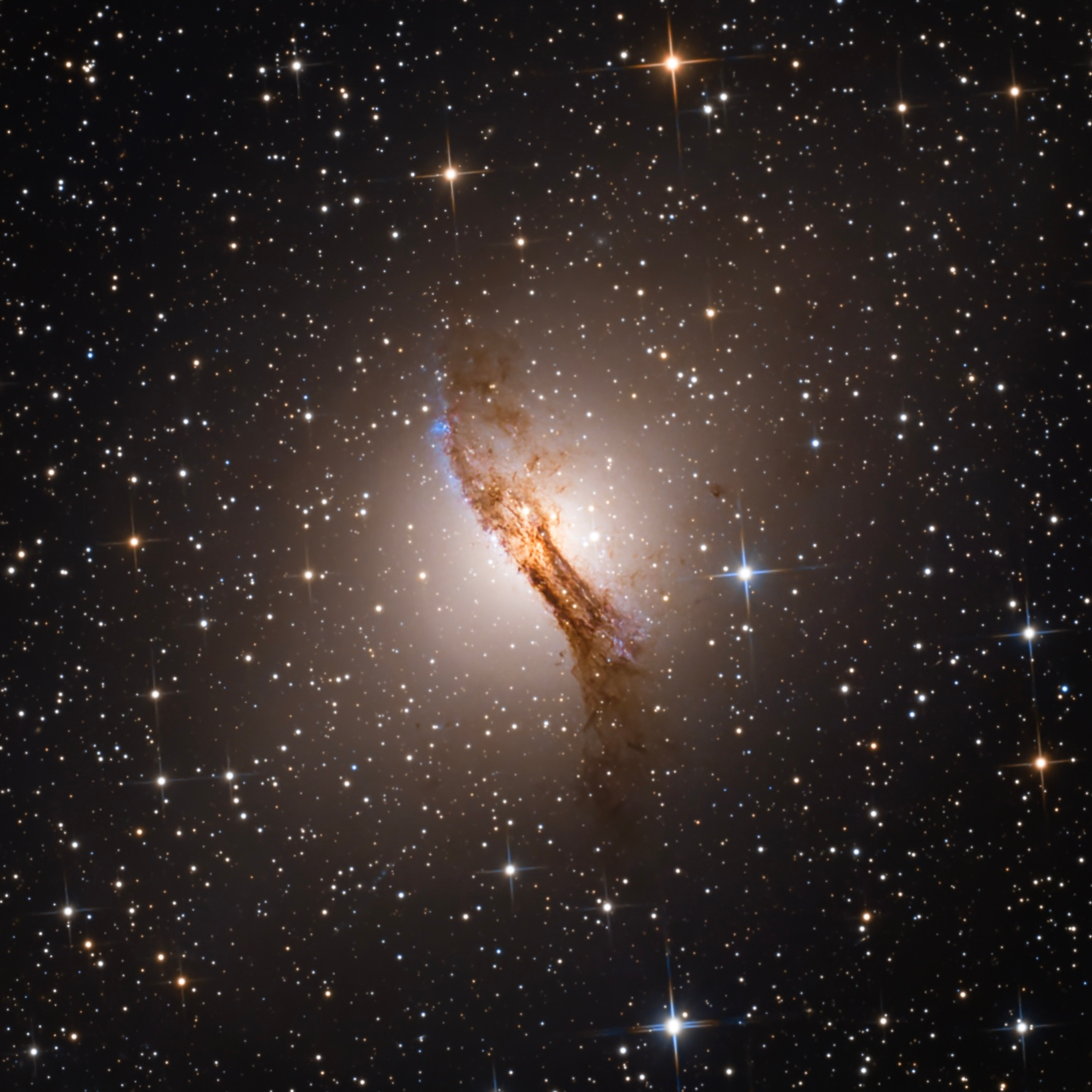 Centaurus A shining through a prominent dark dust lane in a field of foreground stars.
