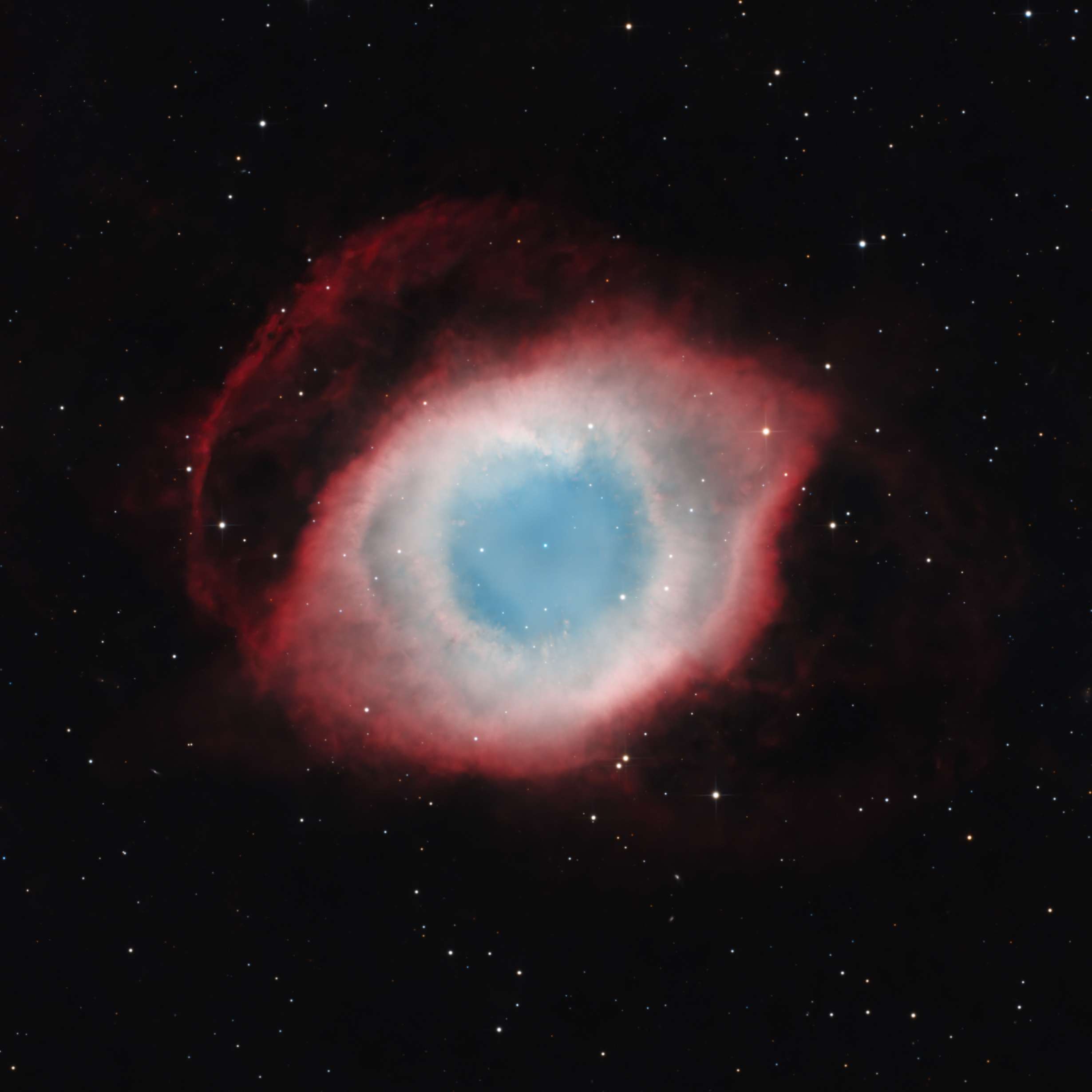 The Helix Nebula appearing as a blue-green eye encircled by a red outer shell.