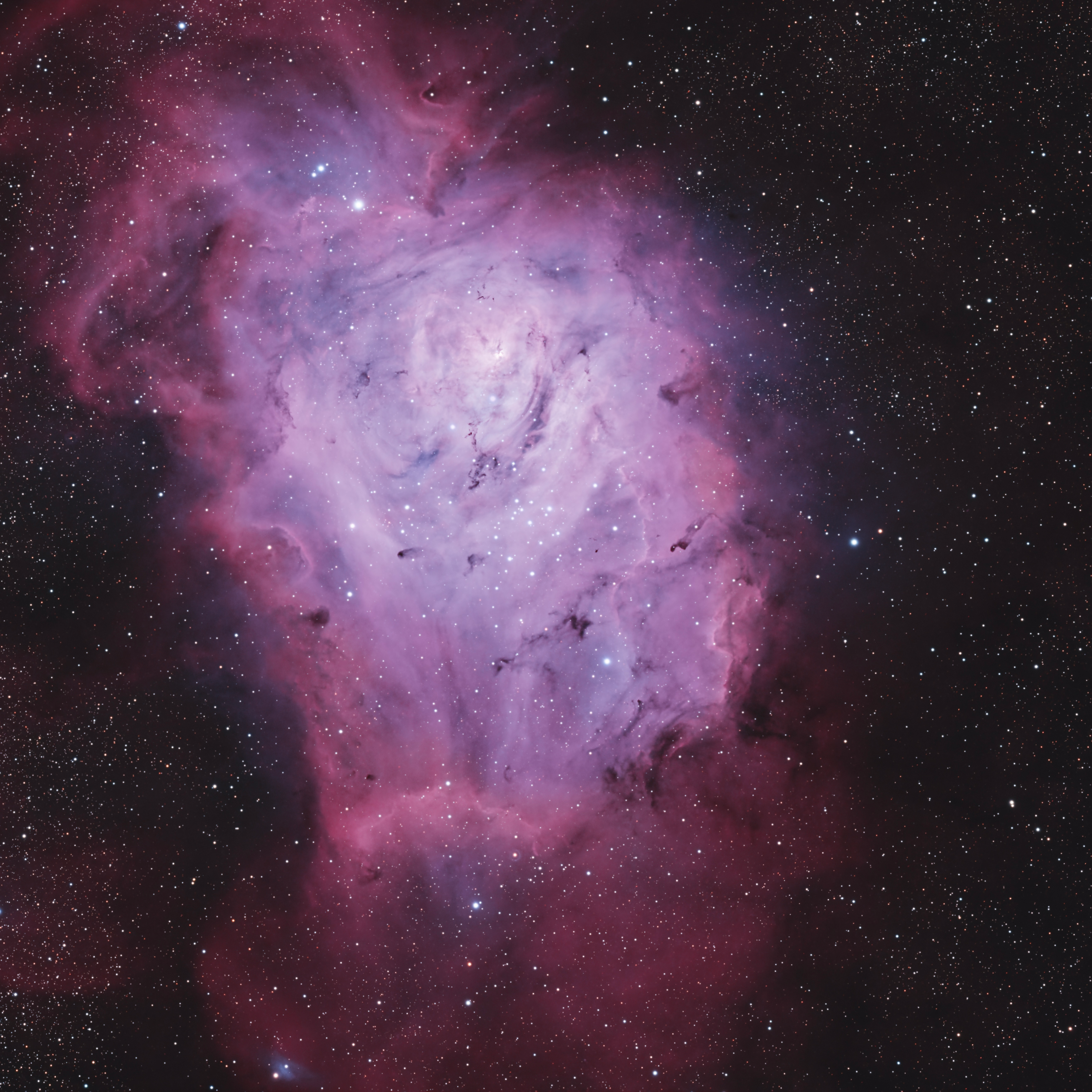A wide panorama showing the Lagoon and Trifid nebulae within a richly detailed Milky Way field.
