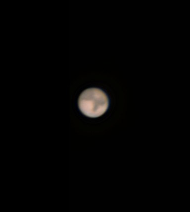 A small orange telescopic disc of Mars set against black space.
