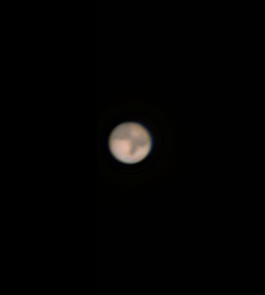 A small orange telescopic disc of Mars set against black space.