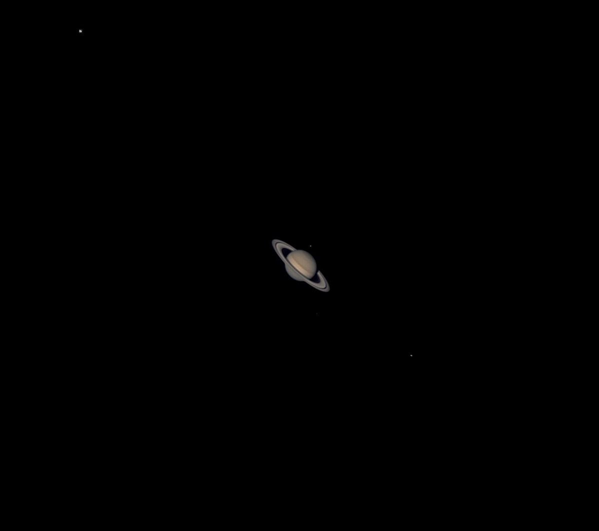 A small telescopic view of Saturn and its rings against black space.